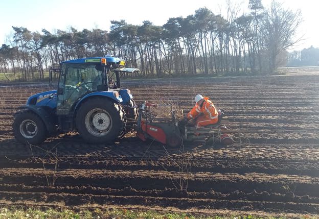 trekker over akkerbouw landschap met een man in oranje reflecterende kleding en witte helm