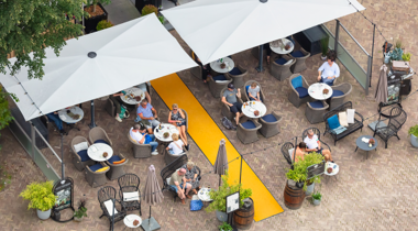 Terras met tafels, mensen en parasols van bovenaf gezien