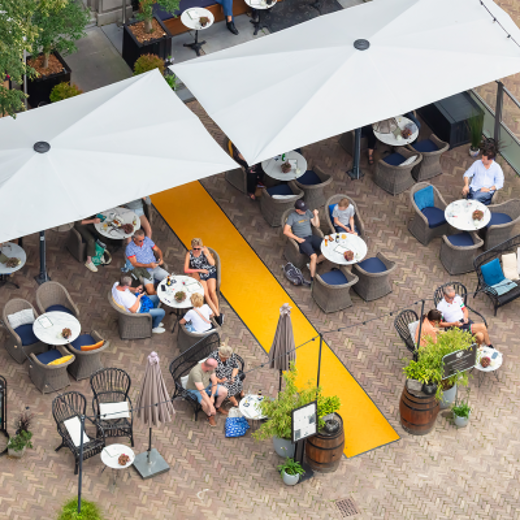 Terras met tafels, mensen en parasols van bovenaf gezien
