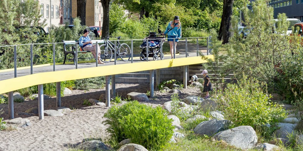 foto van mensen op brug tussen gebouwen in de zon
