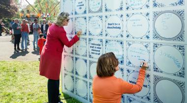 Twee vrouwen schrijven op een muur van grote, blauw-witte tegels tijdens Koningsdag 2025.