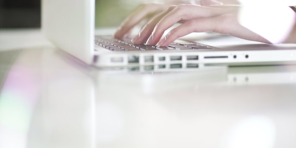 Handen die typen op witte laptop