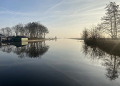 Kanaal bij het ochtendlicht met reflecterende bomen langs de rand in de winter
