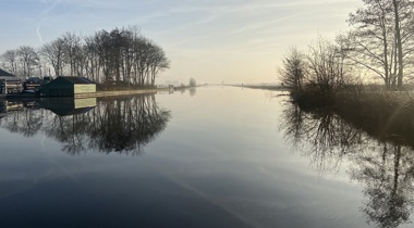 Kanaal bij het ochtendlicht met reflecterende bomen langs de rand in de winter
