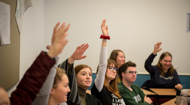 Jongeren in een klas die de hand opsteken