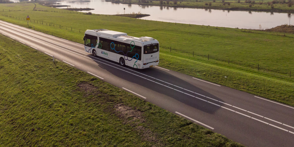 Bus op eenverkeersweg tussen weilanden