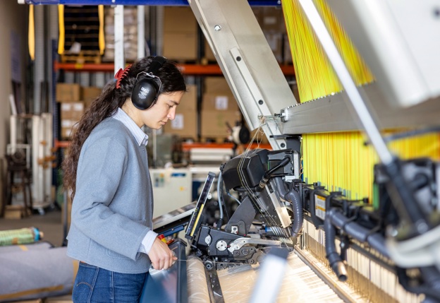 Collega Ezra achter de ultramoderne weefmachine