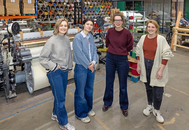 Annemiek Koster met 3 collega's voor een weefmachine in de textielfabriek