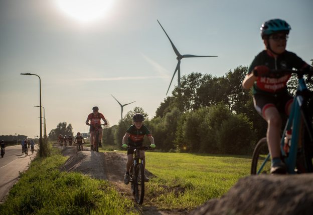 fietsers in tenu en fietshelm fietsen over bergjes zand