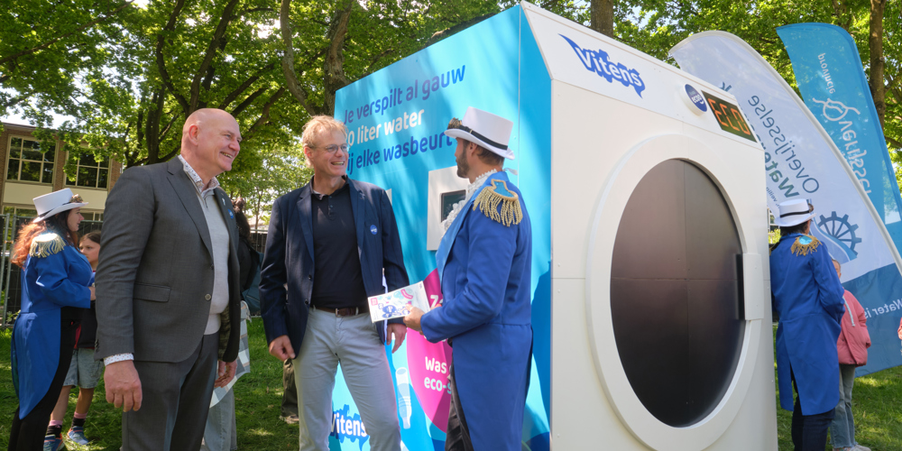 Grote wasmachine van Vitens met mensen eromheen