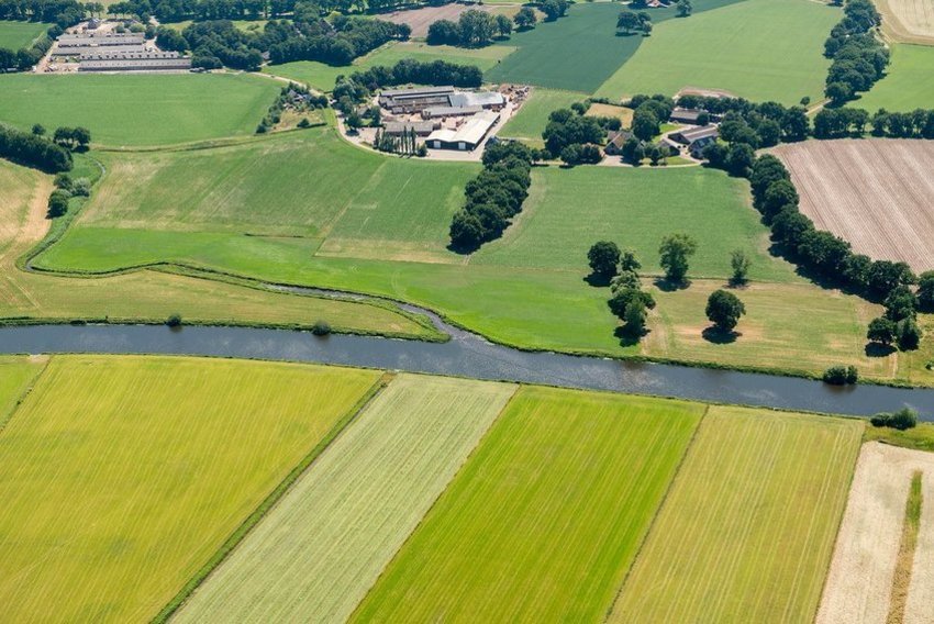 Rivier en aan beide kanten landbouwgrond, boerderijen en bomen